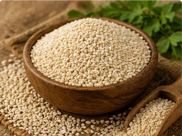Sesame seeds in a wooden bowl with green leaves behind